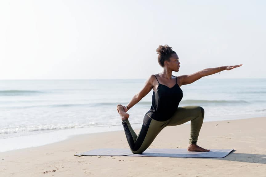 woman practicing yoga on the beach